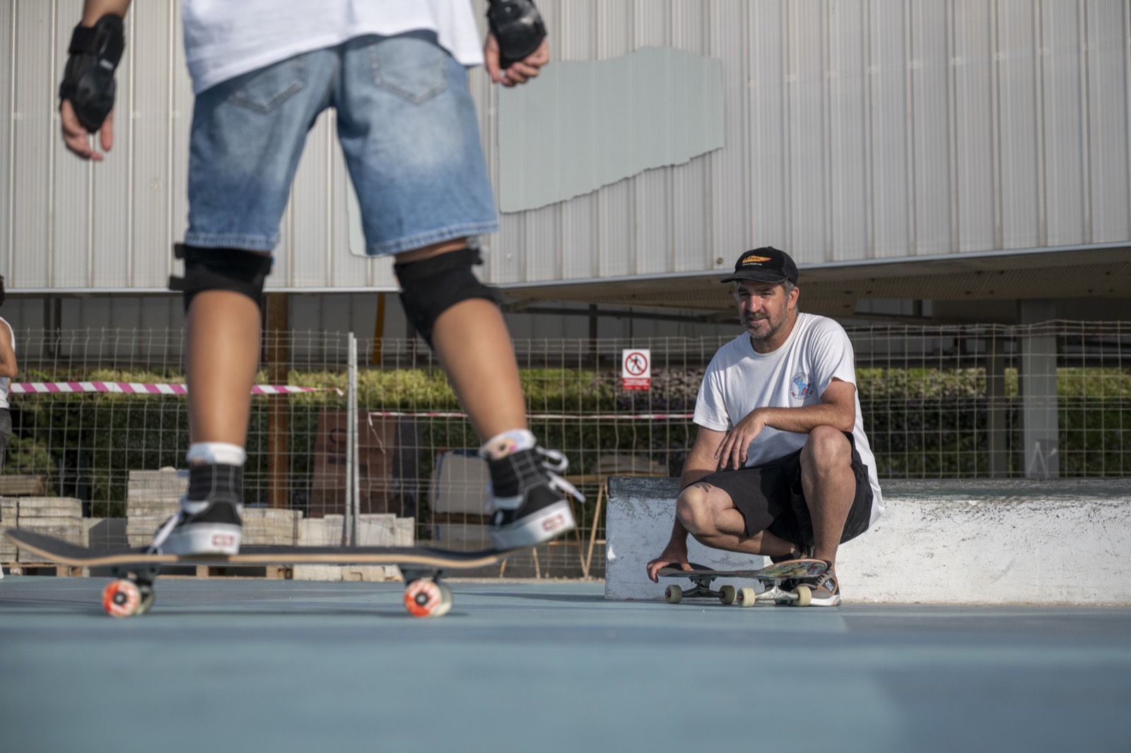 Un monitor enseña a un peque en el skatepark